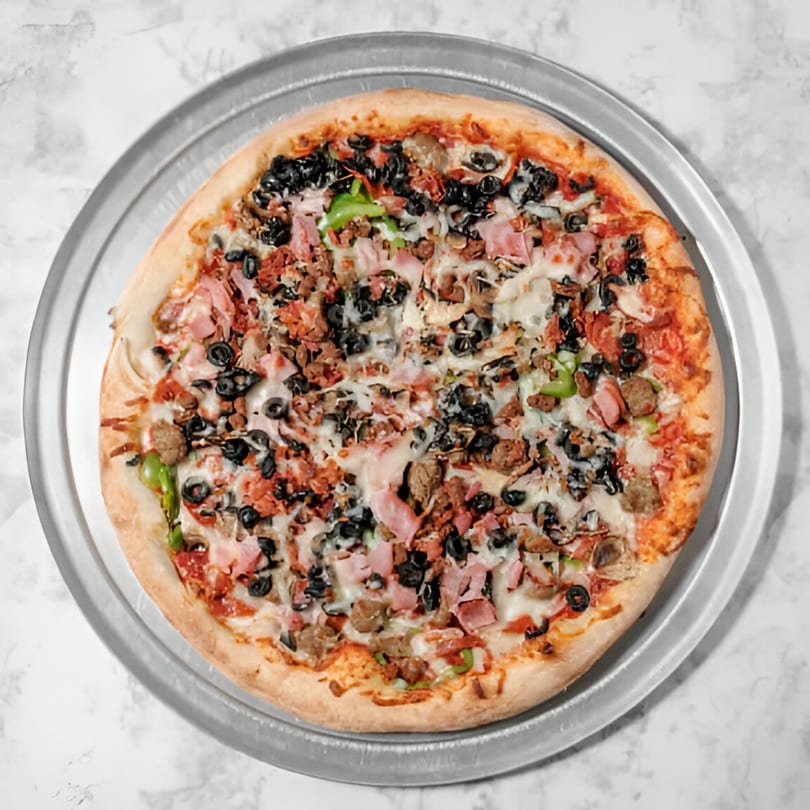 A whole Pointer's Pizza with various toppings including black olives, ham, and green peppers.